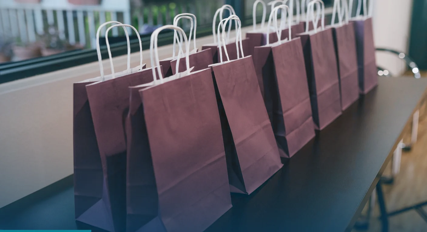 Row of gift bags lined up on a table for guests at a brand event