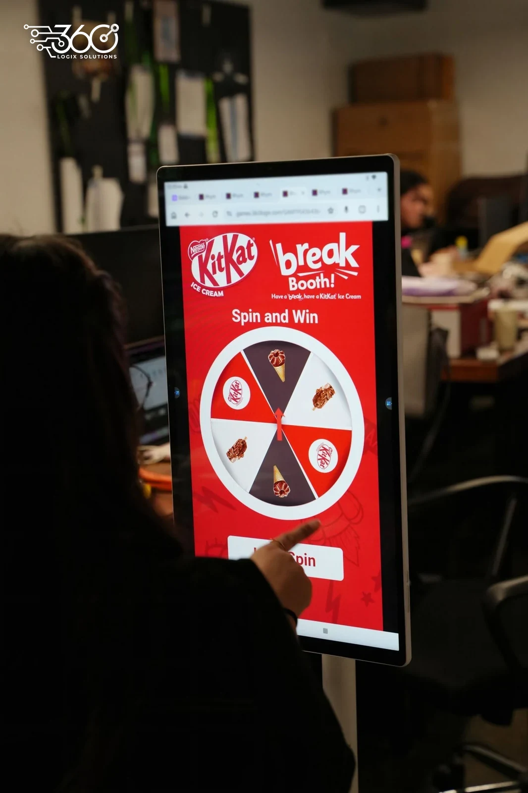 A hand tapping our Spin and Win game for KitKat on a portrait touch-screen kiosk during testing