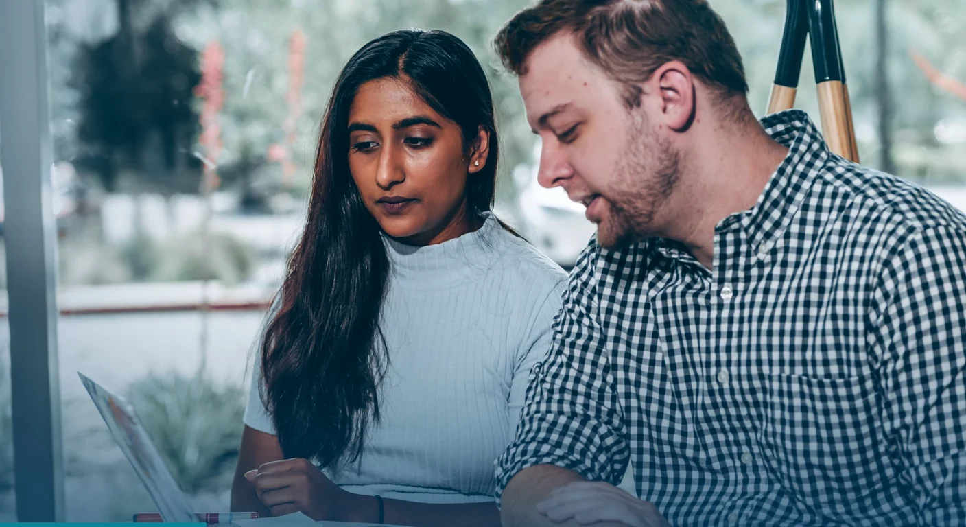 Two colleagues sitting side by side, going over a plan on a laptop