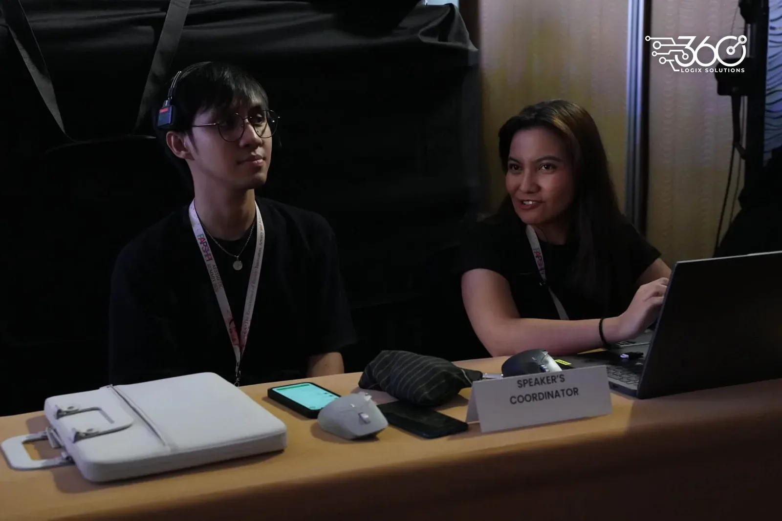 Two team members in PAPSHPI Aesthetic Summit 2026 lanyards at the Speaker's Coordinator desk with a laptop.